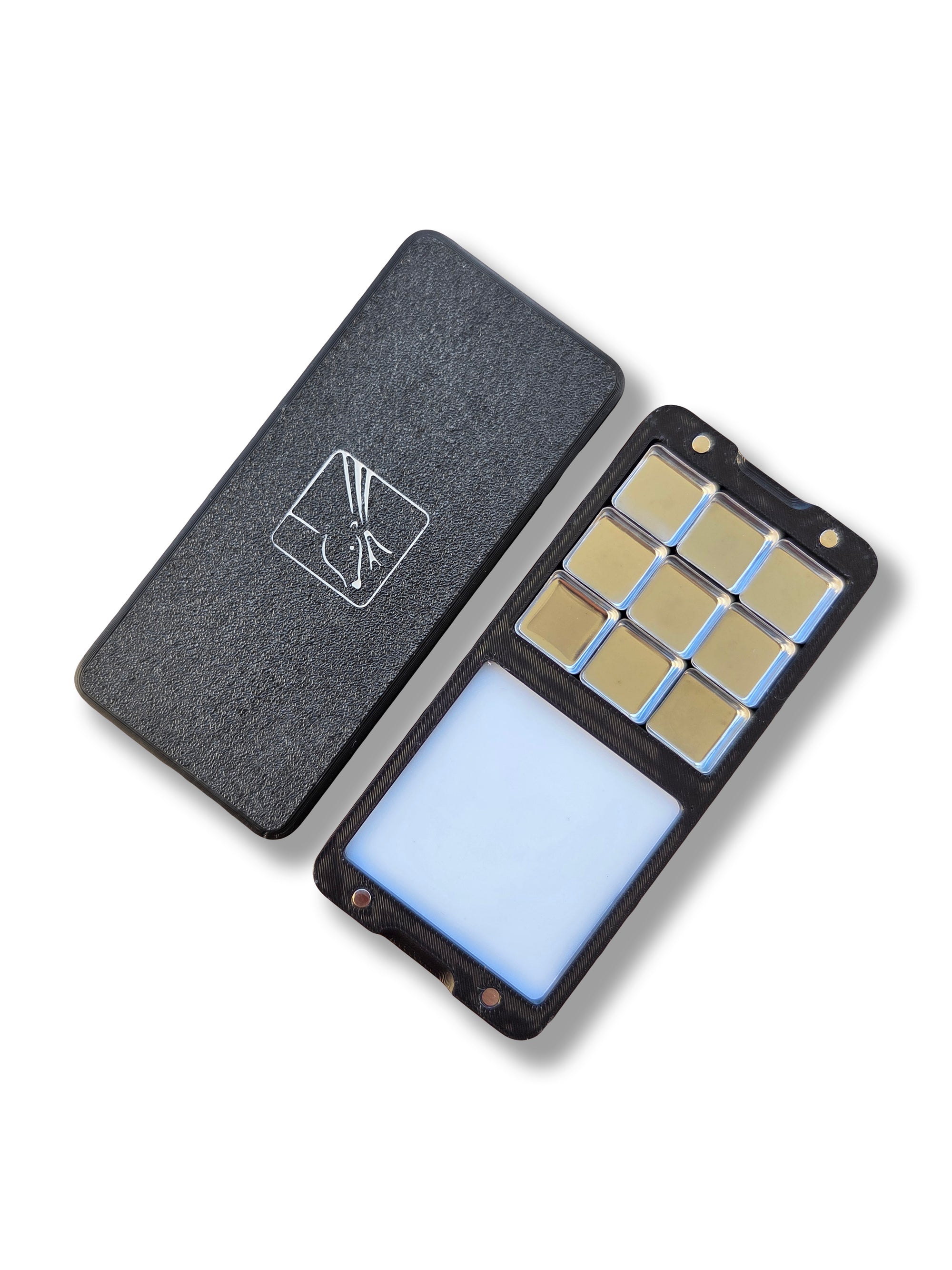 Two halves of an Arwil Art and Design Classic palette on a white background, watercolour paint pans half empty