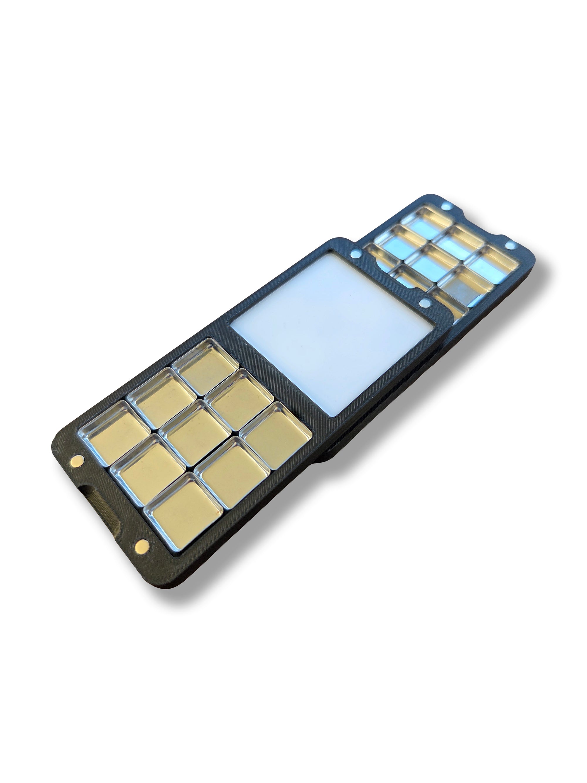 Two halves of an Arwil Art and Design Classic palette stacked, on a white background, watercolour paint pans empty